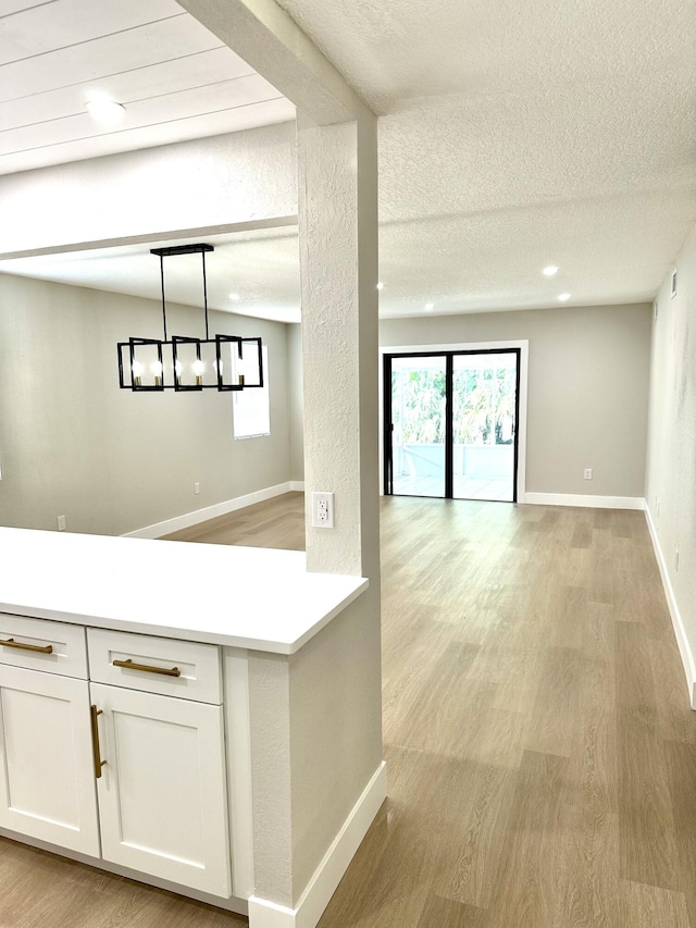 kitchen with light wood finished floors, white cabinets, open floor plan, light countertops, and a textured ceiling
