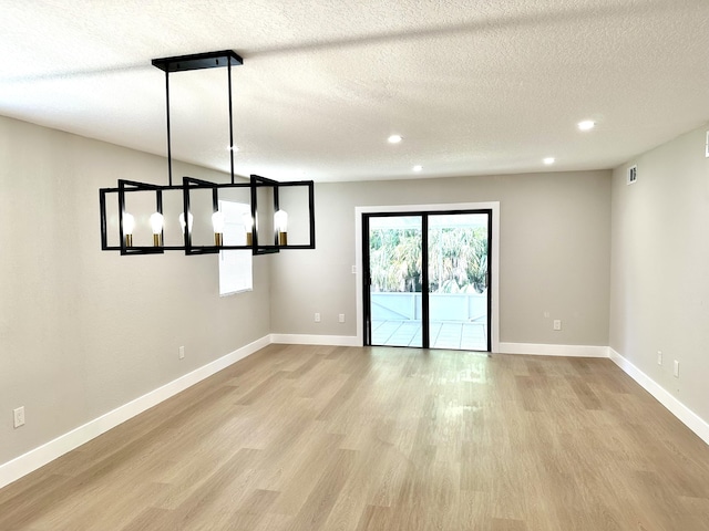 unfurnished dining area featuring light wood finished floors, a textured ceiling, recessed lighting, and baseboards