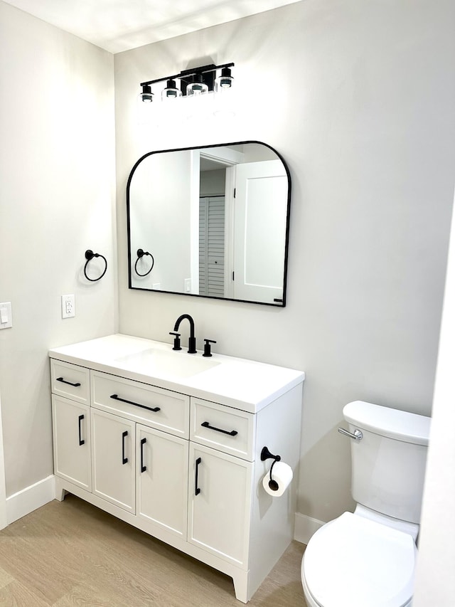 bathroom featuring baseboards, toilet, vanity, and wood finished floors