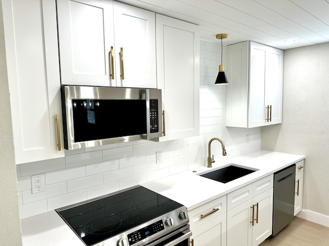 kitchen with appliances with stainless steel finishes, a sink, tasteful backsplash, and white cabinetry