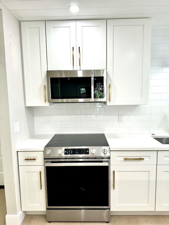 kitchen featuring stainless steel appliances, white cabinetry, light countertops, and backsplash