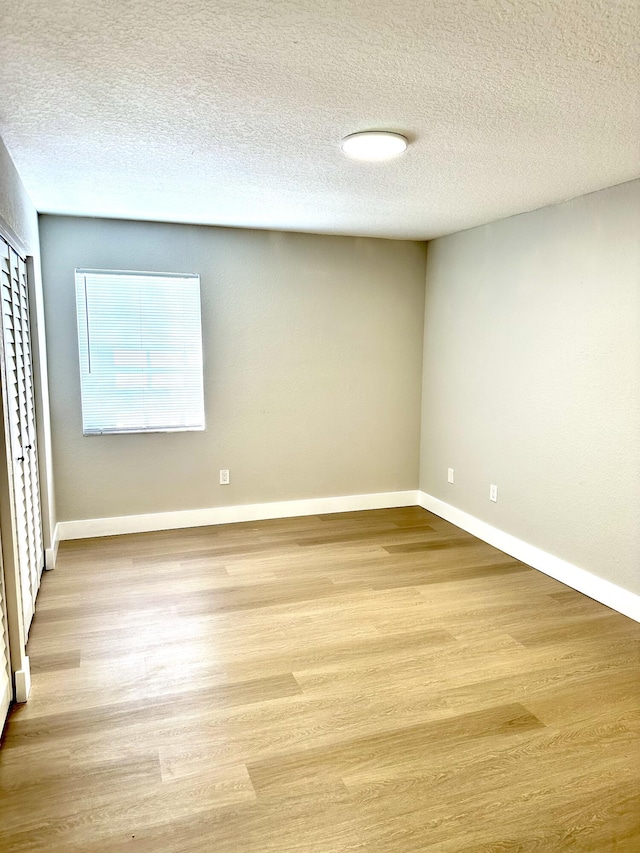 empty room featuring wood finished floors, baseboards, and a textured ceiling