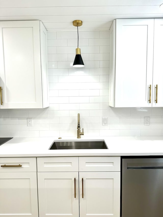 kitchen with stainless steel dishwasher, a sink, white cabinets, and light countertops