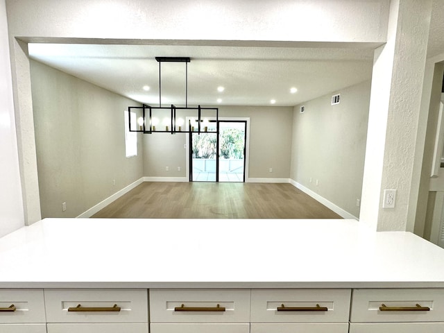 unfurnished dining area with light wood finished floors, recessed lighting, baseboards, and a chandelier