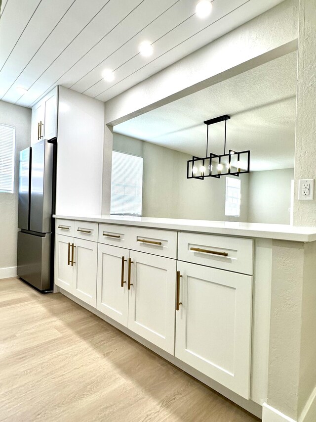 kitchen featuring freestanding refrigerator, light wood-style flooring, light countertops, and white cabinetry
