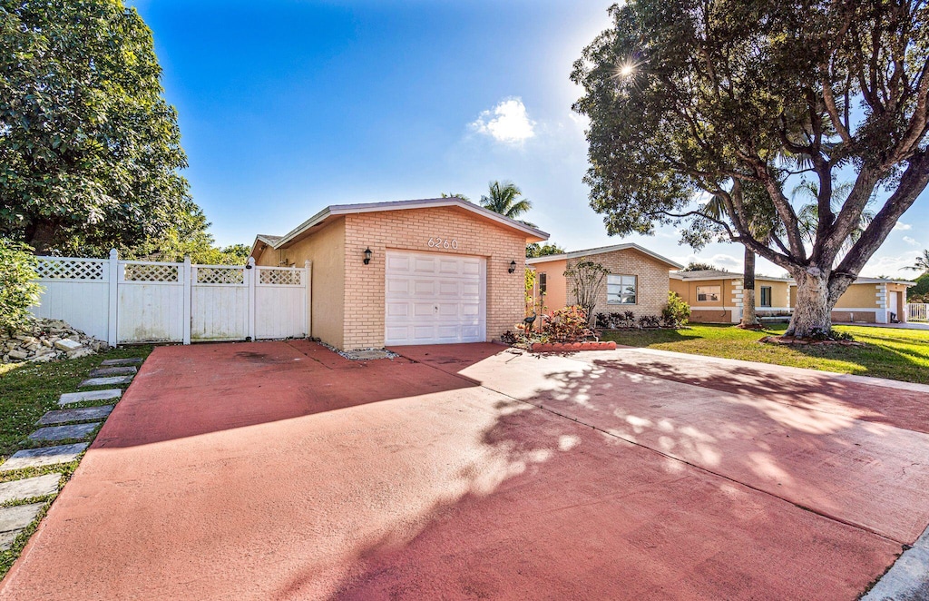 6260 SW 10th Ct, North Lauderdale, FL 33068 - view of front facade with brick siding, driveway, fence, and a garage