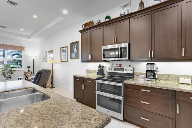 7779 Butera Plz, Delray Beach, FL 33446 - kitchen with appliances with stainless steel finishes, a sink, dark brown cabinetry, light stone counters, and baseboards