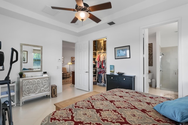 7779 Butera Plz, Delray Beach, FL 33446 - tiled bedroom featuring a walk in closet, a closet, a tray ceiling, a ceiling fan, and connected bathroom