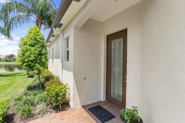 7779 Butera Plz, Delray Beach, FL 33446 - entrance to property with stucco siding, a water view, and a lawn