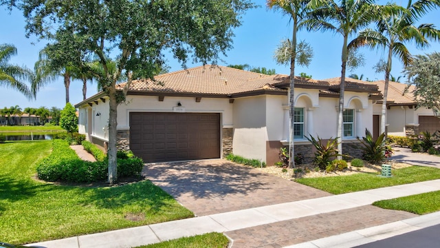 7779 Butera Plz, Delray Beach, FL 33446 - mediterranean / spanish-style house with stone siding, stucco siding, a tiled roof, a garage, and a front yard