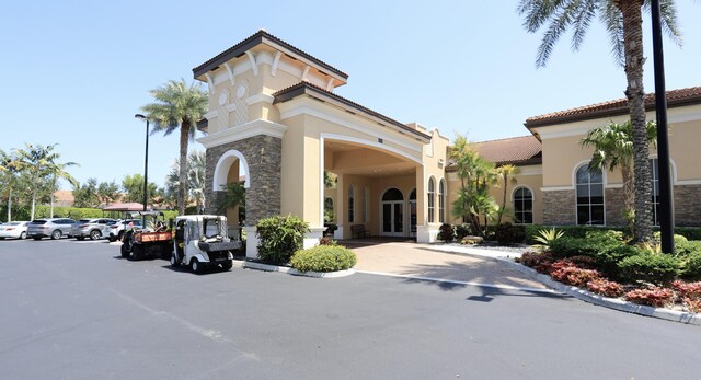 7779 Butera Plz, Delray Beach, FL 33446 - view of front facade featuring stone siding, stucco siding, a tiled roof, and french doors