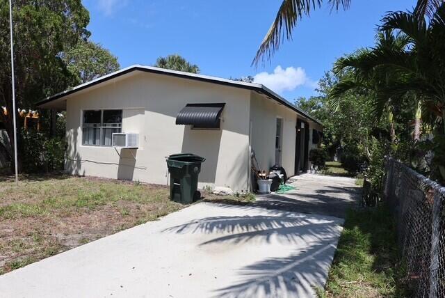 1454 NE 2nd Ct, Boca Raton, FL 33432 - view of side of home with fence, stucco siding, and cooling unit