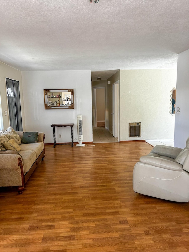 1454 NE 2nd Ct, Boca Raton, FL 33432 - living room featuring heating unit, light wood-style flooring, a textured ceiling, and baseboards