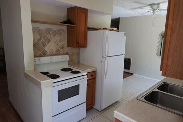 1454 NE 2nd Ct, Boca Raton, FL 33432 - kitchen featuring white appliances, a sink, light tile patterned floors, and light countertops