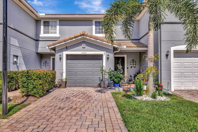 2556 Marshfield Ct, Port Saint Lucie, FL 34953 - townhome / multi-family property with stucco siding, a tile roof, decorative driveway, and a garage