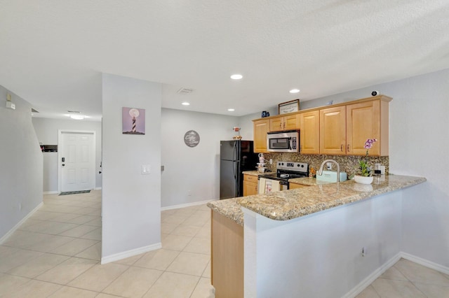 2556 Marshfield Ct, Port Saint Lucie, FL 34953 - kitchen featuring appliances with stainless steel finishes, light stone counters, decorative backsplash, light tile patterned flooring, and a peninsula