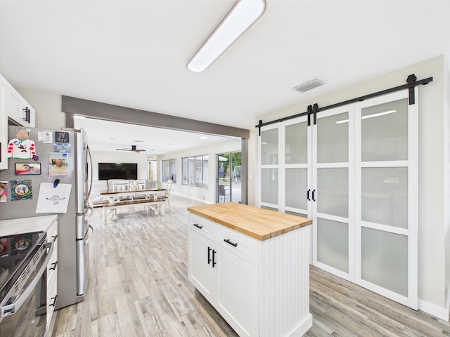 kitchen with a barn door, wooden counters, electric range, and light wood-style flooring