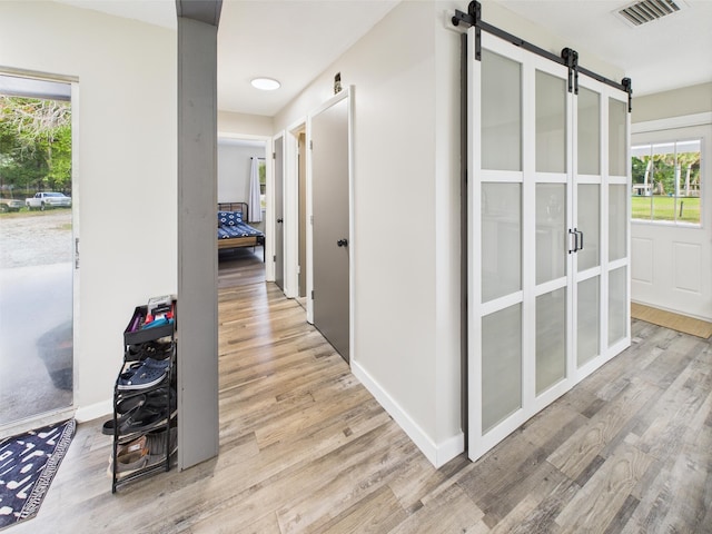 corridor with a barn door, wood finished floors, and healthy amount of natural light