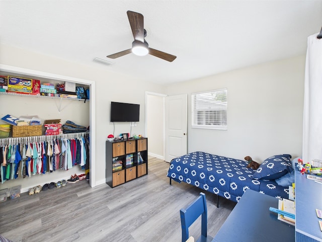 bedroom featuring wood finished floors, a closet, ceiling fan, and baseboards