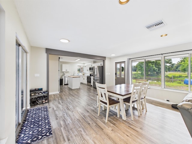 dining room featuring light wood finished floors, baseboards, and recessed lighting