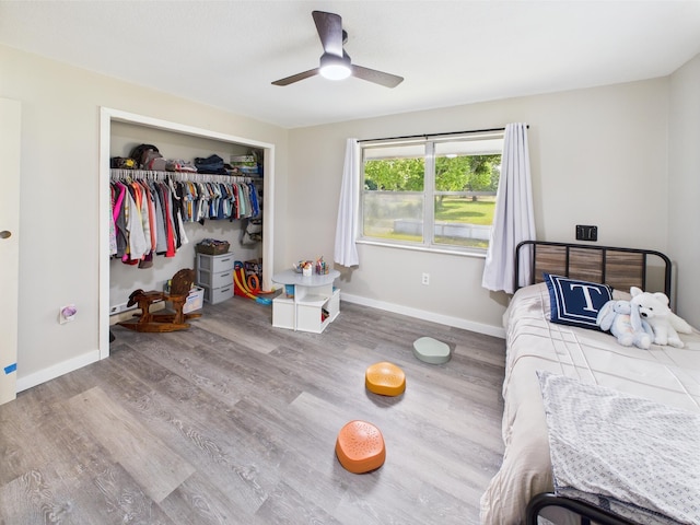 bedroom featuring wood finished floors, a closet, baseboards, and ceiling fan
