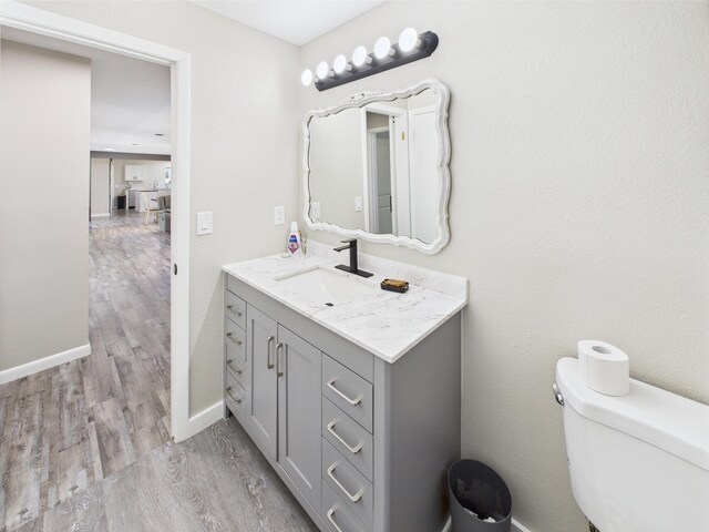 bathroom featuring wood finished floors, vanity, toilet, and baseboards