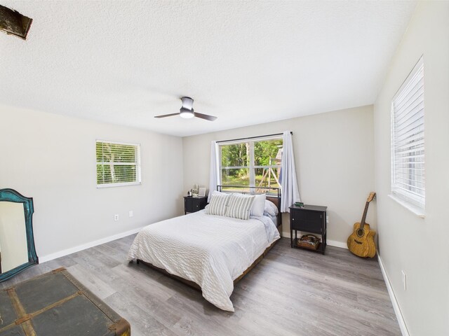 bedroom with wood finished floors, ceiling fan, baseboards, and a textured ceiling