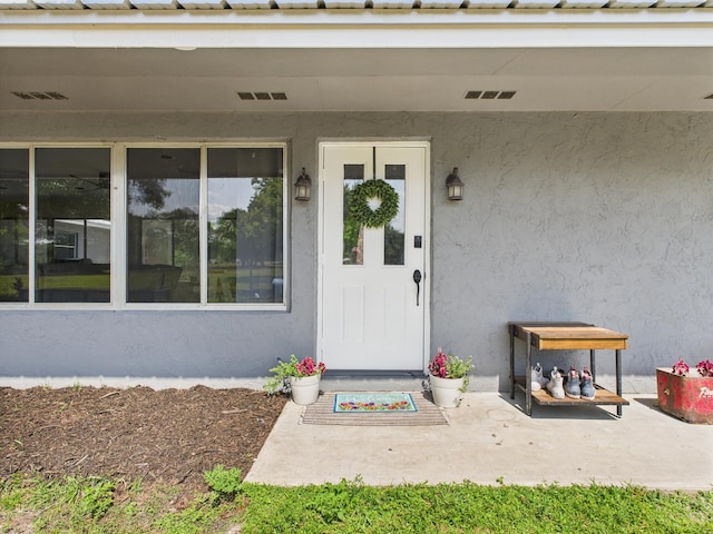 doorway to property featuring stucco siding