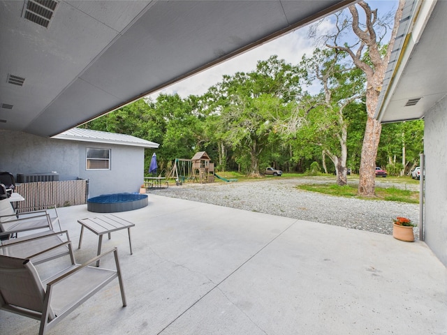 view of patio / terrace with a playground and view of wooded area
