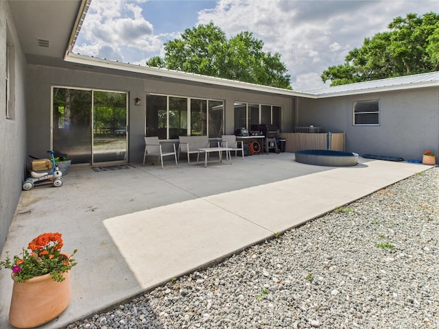 back of property featuring stucco siding, a patio, and metal roof