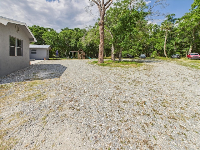 view of yard with a playground and view of wooded area