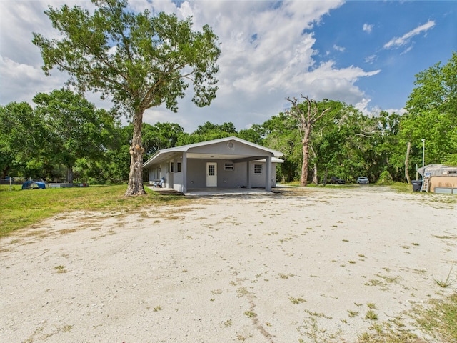 view of front facade featuring a carport and view of wooded area