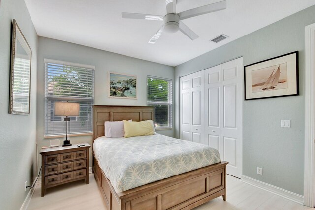 bedroom featuring baseboards, a closet, a ceiling fan, and light wood-style flooring