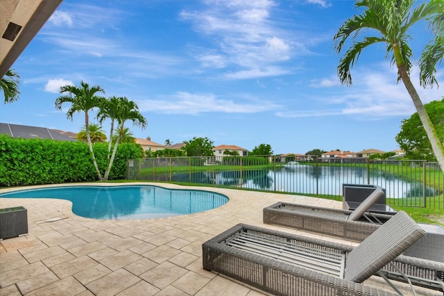view of pool with a patio area, a water view, fence, and a residential view