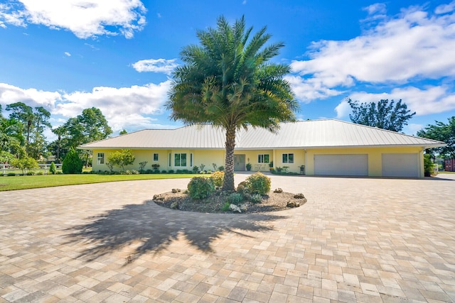 6624 Dillman Rd, West Palm Beach, FL 33413 - view of front facade with curved driveway, metal roof, a garage, and stucco siding