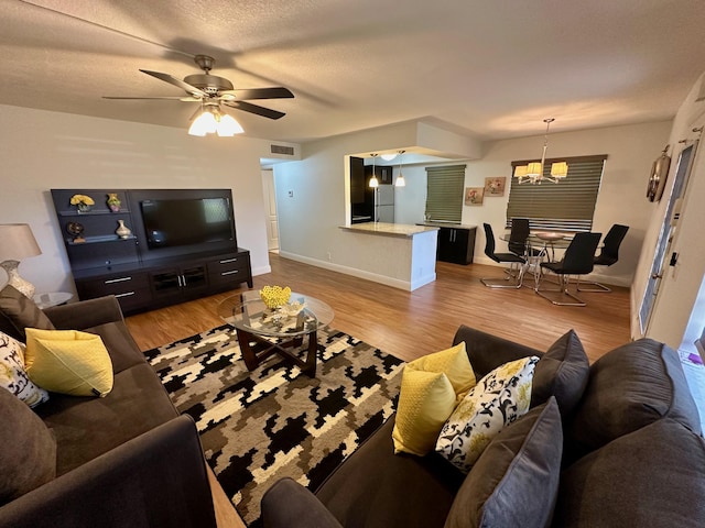 living area featuring a chandelier, wood finished floors, baseboards, and a ceiling fan