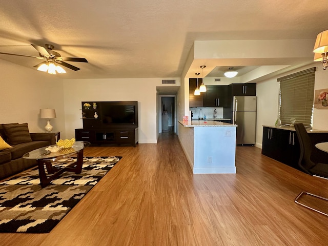 living room with wood finished floors, a ceiling fan, and baseboards