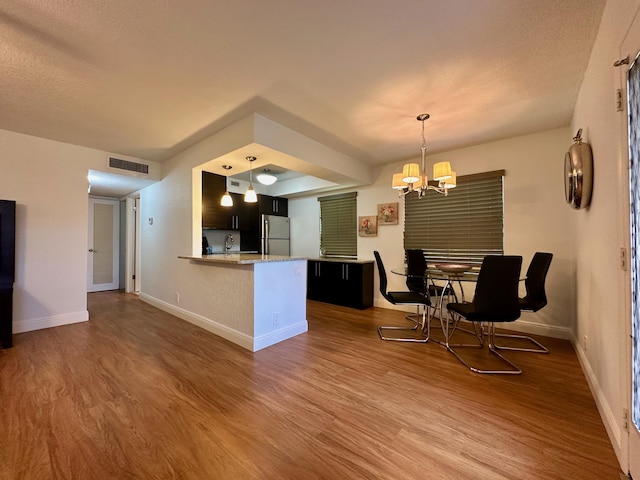 kitchen featuring freestanding refrigerator, a chandelier, baseboards, and wood finished floors