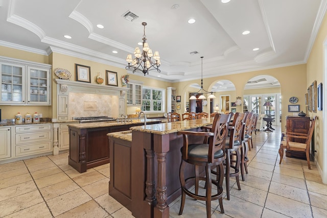 11 Wendy Ln, Stuart, FL 34994 - kitchen with a spacious island, a chandelier, a tray ceiling, ornamental molding, and glass insert cabinets