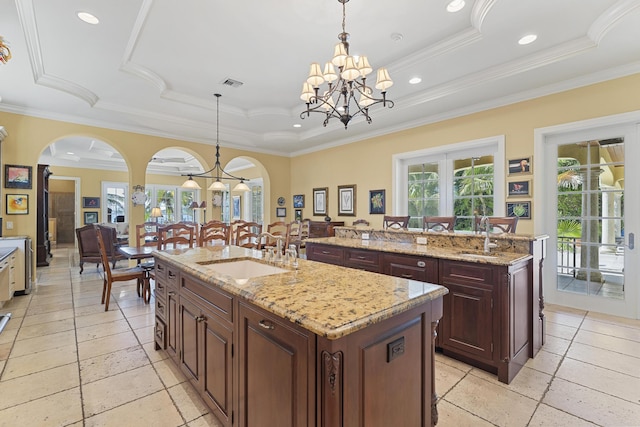 11 Wendy Ln, Stuart, FL 34994 - kitchen with a sink, a kitchen island with sink, a tray ceiling, arched walkways, and crown molding