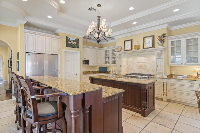 11 Wendy Ln, Stuart, FL 34994 - kitchen with a center island with sink, stainless steel appliances, arched walkways, a sink, and cream cabinetry