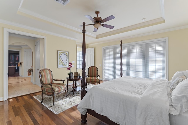 11 Wendy Ln, Stuart, FL 34994 - bedroom featuring a raised ceiling, arched walkways, multiple windows, wood finished floors, and crown molding