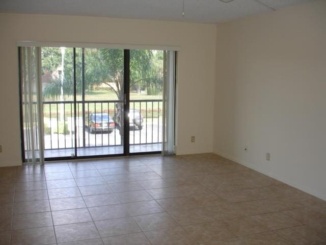 empty room featuring plenty of natural light, tile patterned flooring, and a ceiling fan
