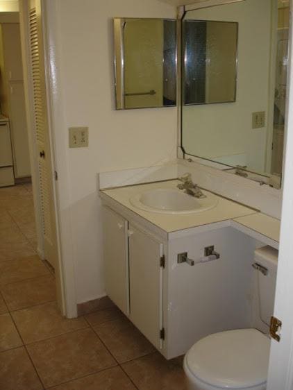 half bathroom with toilet, tile patterned flooring, and vanity