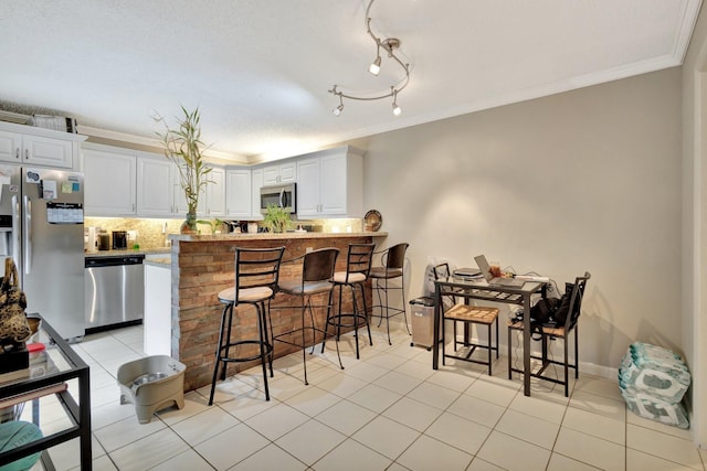 2950 SW 22nd Cir Unit 4C, Delray Beach, FL 33445 - kitchen with stainless steel appliances, ornamental molding, decorative backsplash, a kitchen breakfast bar, and a peninsula