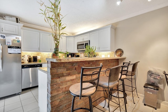 2950 SW 22nd Cir Unit 4C, Delray Beach, FL 33445 - kitchen featuring stainless steel appliances, light tile patterned flooring, backsplash, crown molding, and a textured ceiling