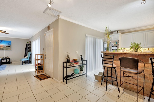 2950 SW 22nd Cir Unit 4C, Delray Beach, FL 33445 - kitchen with light tile patterned floors, a textured ceiling, ornamental molding, baseboards, and a breakfast bar