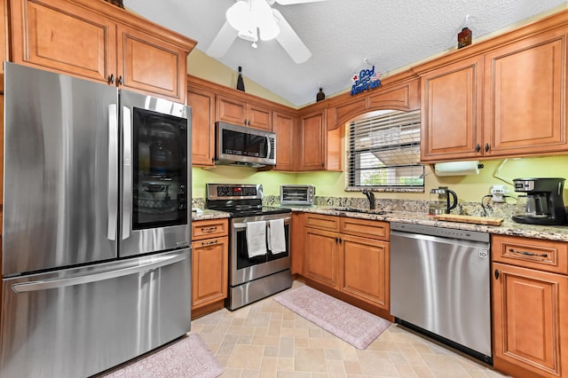 3001 SE Aster Ln Unit 908, Stuart, FL 34994 - kitchen featuring stainless steel appliances, vaulted ceiling, brown cabinetry, light stone countertops, and a ceiling fan