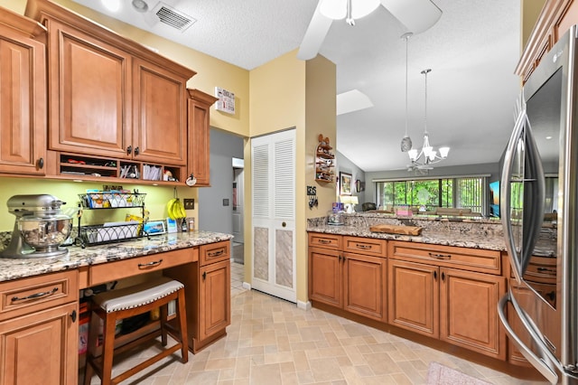 3001 SE Aster Ln Unit 908, Stuart, FL 34994 - kitchen featuring stainless steel fridge, brown cabinets, pendant lighting, and light stone countertops
