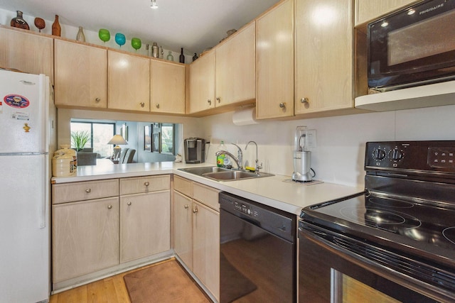 kitchen with black appliances, a sink, light brown cabinetry, and light countertops